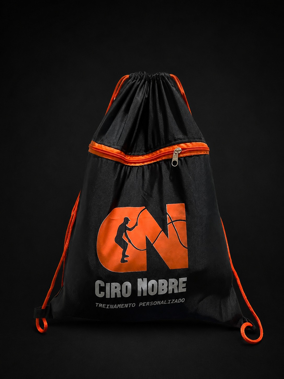 Sacochila oficial Ciro Nobre, preta com zíper e cordões laranja e a logo CN